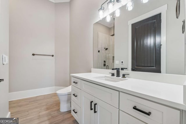 full bathroom featuring toilet, wood finished floors, vanity, baseboards, and a stall shower