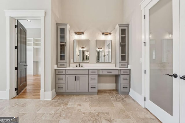 full bath featuring french doors, vanity, and baseboards