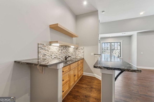 kitchen featuring open shelves, a breakfast bar area, a peninsula, and backsplash