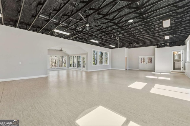 unfurnished living room with a ceiling fan and baseboards