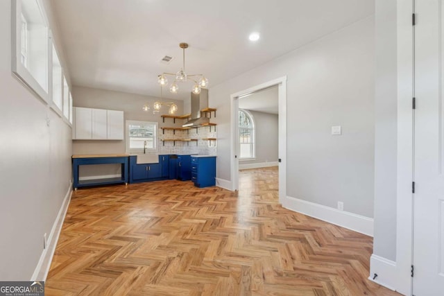 interior space featuring island exhaust hood, visible vents, a healthy amount of sunlight, a sink, and blue cabinets