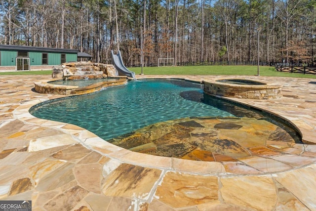 view of pool with a pool with connected hot tub, fence, a lawn, and a water slide