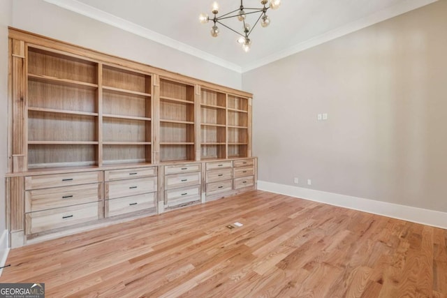 unfurnished room with an inviting chandelier, baseboards, wood finished floors, and ornamental molding