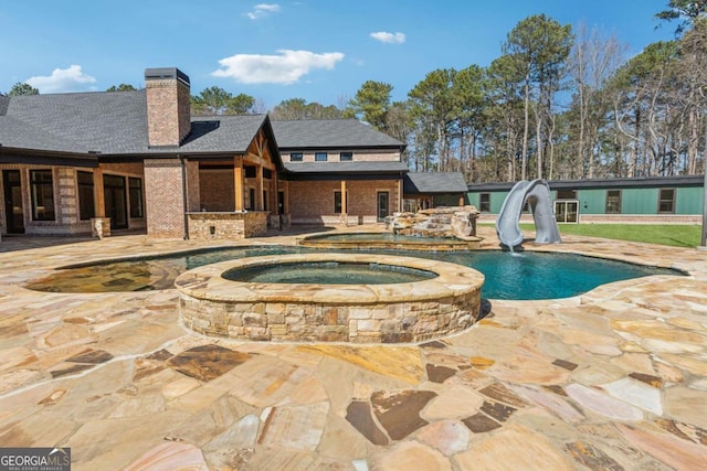 view of pool with a pool with connected hot tub, a water slide, and a patio