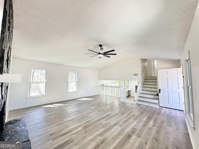 unfurnished living room with baseboards, lofted ceiling, ceiling fan, wood finished floors, and a textured ceiling