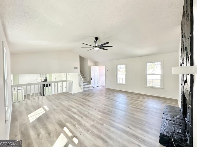 101 Summer Pond Trl, Lawrenceville, GA 30046 - unfurnished living room with a textured ceiling, a ceiling fan, wood finished floors, a fireplace, and vaulted ceiling