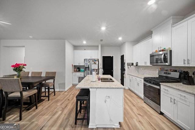 kitchen with light wood-style floors, appliances with stainless steel finishes, backsplash, and a sink