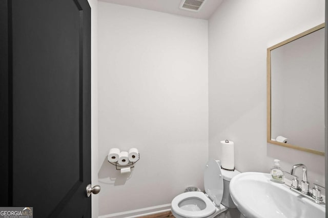 bathroom with baseboards, visible vents, a sink, and toilet