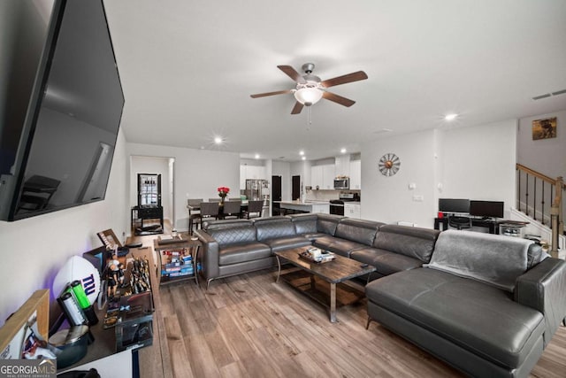 living area with light wood finished floors, recessed lighting, visible vents, ceiling fan, and stairs