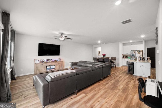 living room with baseboards, visible vents, a ceiling fan, light wood-style floors, and recessed lighting