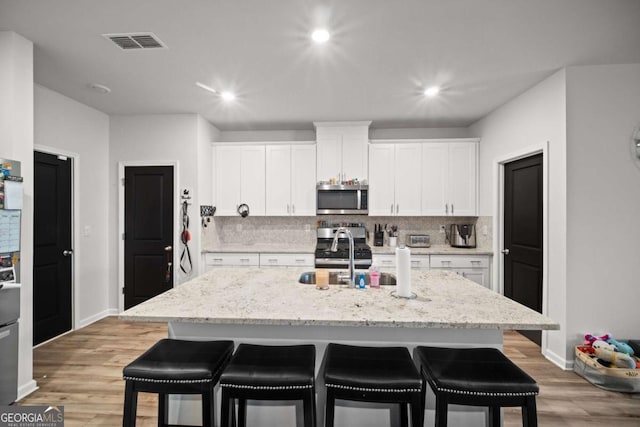 kitchen with stainless steel microwave, a kitchen bar, a sink, and backsplash