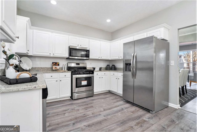 kitchen featuring light stone counters, recessed lighting, white cabinetry, appliances with stainless steel finishes, and light wood finished floors