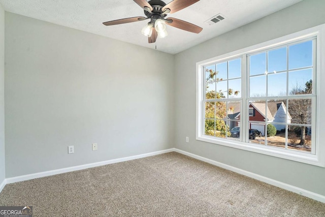 unfurnished room featuring a textured ceiling, carpet, visible vents, and baseboards