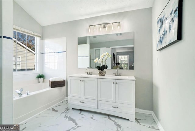 full bathroom with marble finish floor, double vanity, a sink, baseboards, and a bath