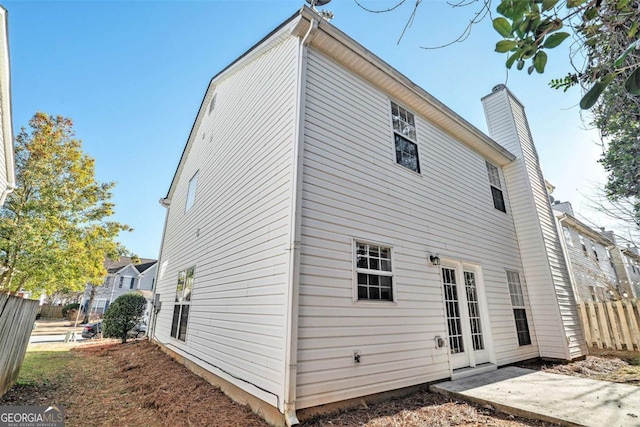 back of property with fence, a chimney, and a patio