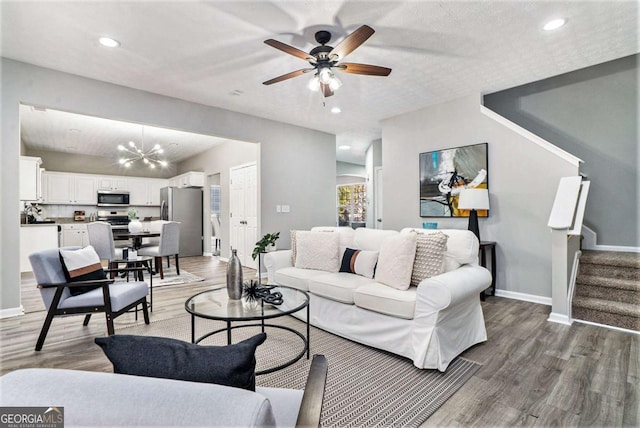 living area featuring light wood-style floors, stairs, baseboards, and recessed lighting