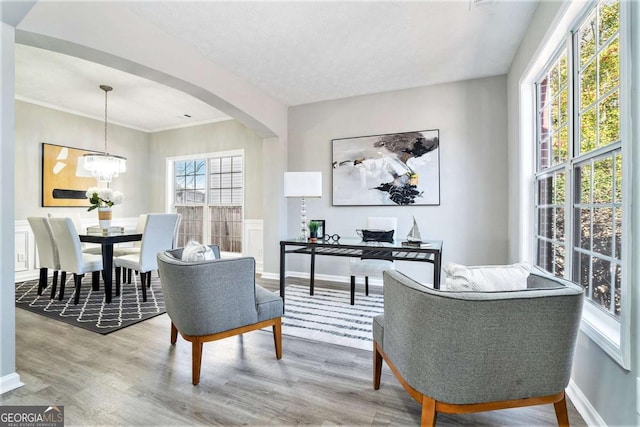 interior space with arched walkways, a textured ceiling, a notable chandelier, wood finished floors, and baseboards