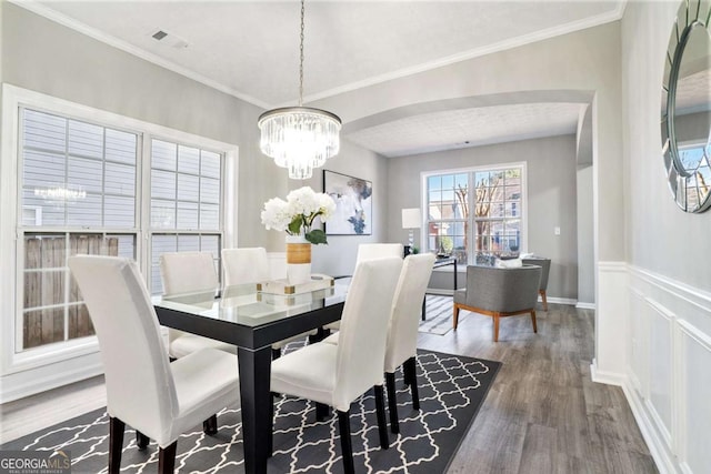 dining room with baseboards, wainscoting, wood finished floors, crown molding, and a notable chandelier