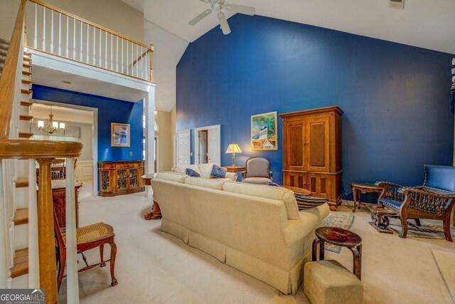 carpeted living area featuring high vaulted ceiling and ceiling fan with notable chandelier