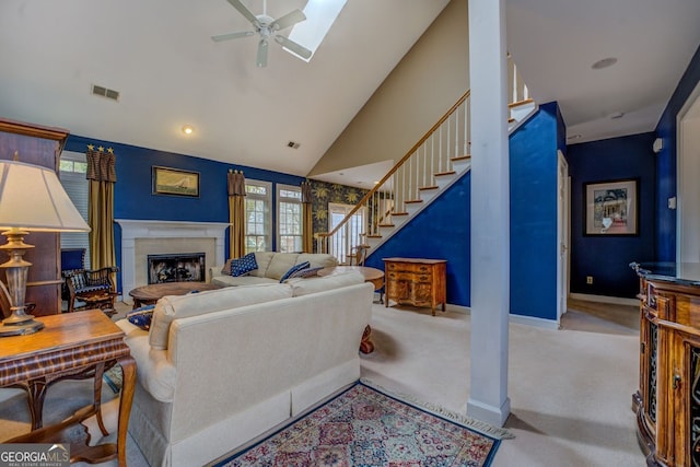 living room featuring carpet floors, a fireplace, visible vents, ceiling fan, and stairs