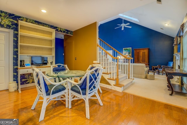 dining room with lofted ceiling, ceiling fan, stairs, and wood finished floors