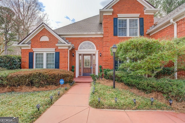 traditional home with a shingled roof and brick siding