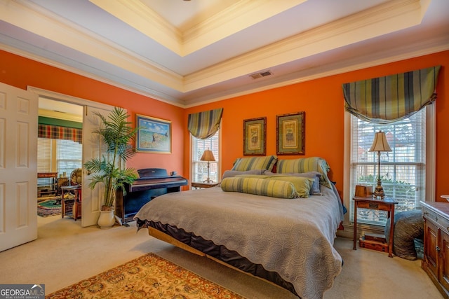 carpeted bedroom with a tray ceiling, visible vents, and crown molding