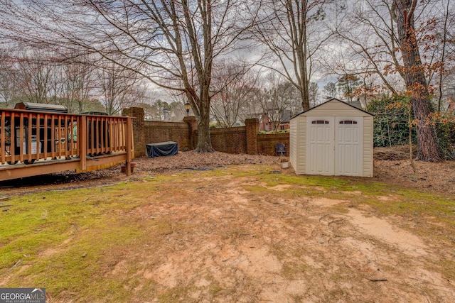 view of yard with a storage shed, an outbuilding, a wooden deck, and fence