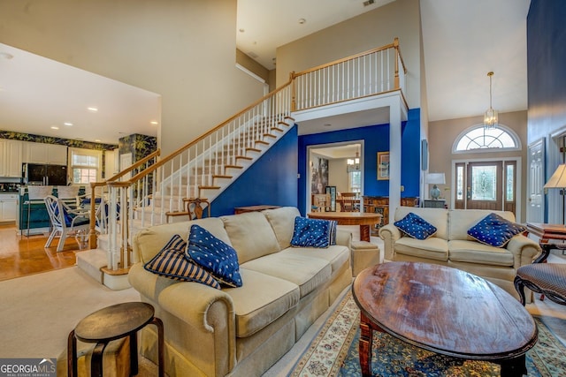 living area featuring a wealth of natural light, wood finished floors, a high ceiling, and stairs