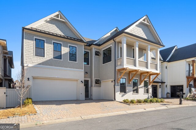 view of front facade with a garage, decorative driveway, fence, and a balcony