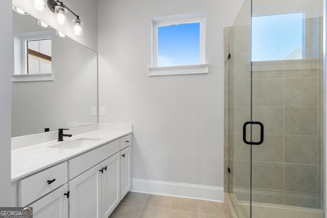 bathroom featuring a stall shower, tile patterned flooring, baseboards, and vanity