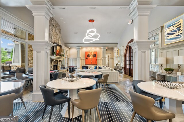 living area featuring lofted ceiling, stone finish flooring, ceiling fan with notable chandelier, and a fireplace