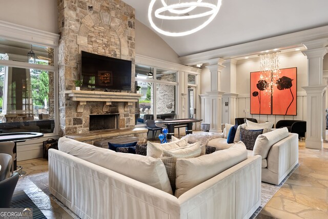 dining area with decorative columns, high vaulted ceiling, stone tile flooring, and a stone fireplace