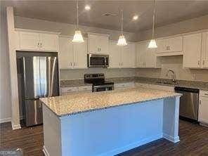 kitchen with a kitchen island, a sink, white cabinets, appliances with stainless steel finishes, and dark wood finished floors