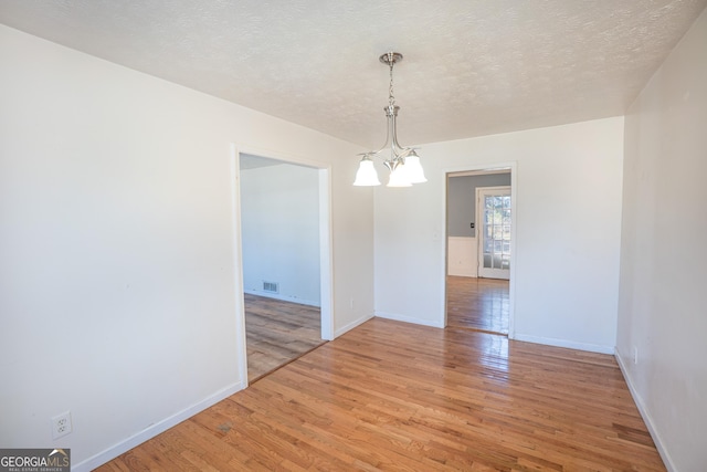 unfurnished dining area featuring light wood-style flooring, baseboards, and a notable chandelier