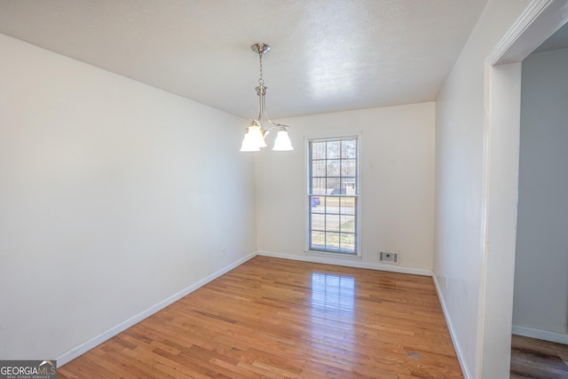 spare room with light wood finished floors, baseboards, and visible vents