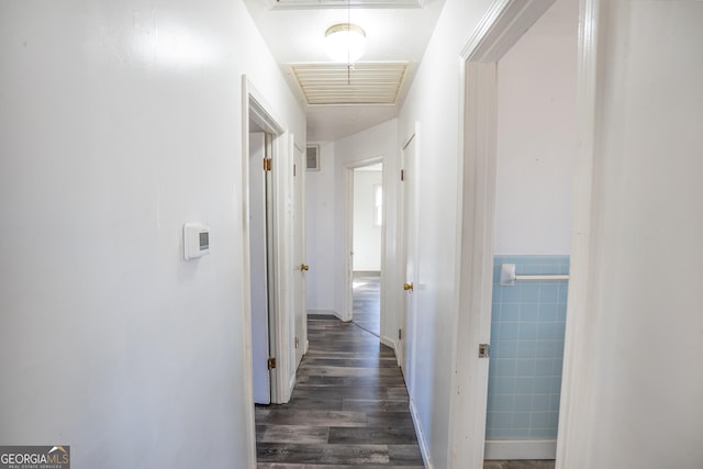 hallway featuring wood finished floors, visible vents, and baseboards