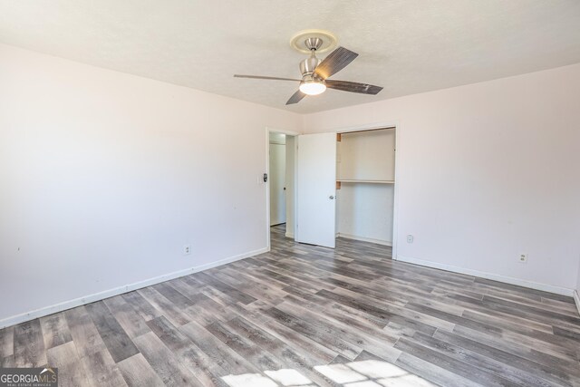 unfurnished bedroom with wood finished floors, a closet, a ceiling fan, and baseboards