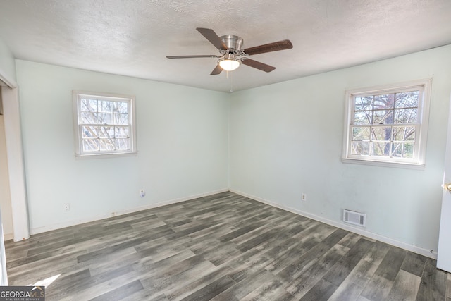 interior space featuring wood finished floors, visible vents, a textured ceiling, and multiple windows