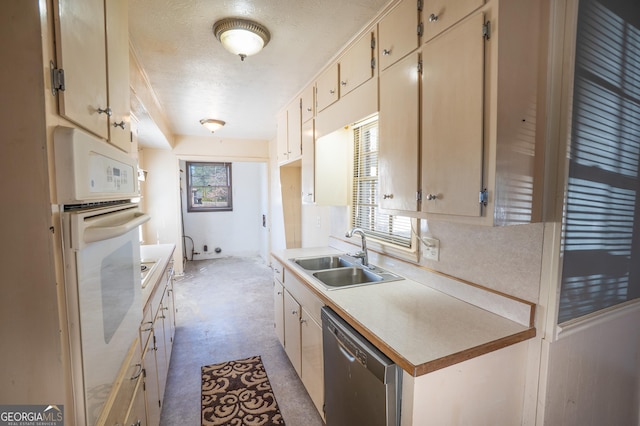 kitchen featuring stainless steel dishwasher, a sink, a textured ceiling, oven, and light countertops