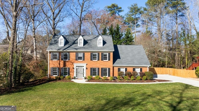 view of front of house with a front lawn, fence, and brick siding