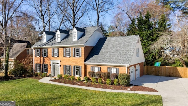 view of front of property with brick siding, roof with shingles, fence, driveway, and a front lawn