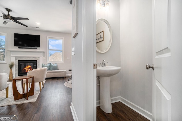 bathroom featuring visible vents, baseboards, a glass covered fireplace, wood finished floors, and a sink