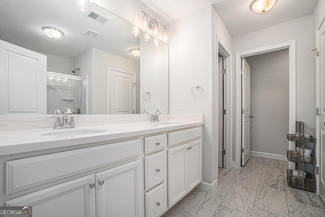 full bath with double vanity, marble finish floor, baseboards, and a sink