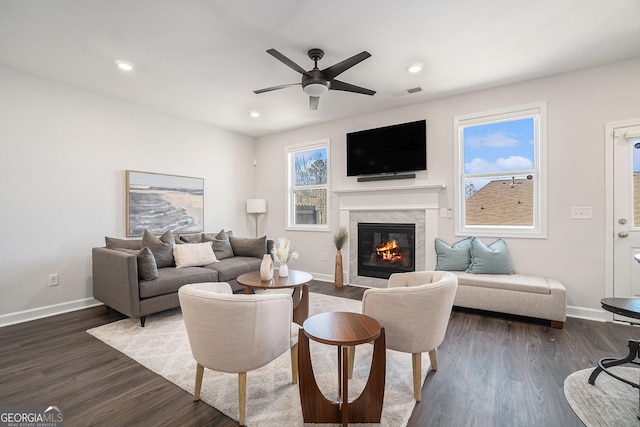 living room featuring baseboards, visible vents, a premium fireplace, dark wood-type flooring, and recessed lighting