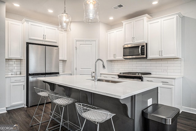 kitchen featuring dark wood finished floors, a breakfast bar area, stainless steel appliances, and a sink