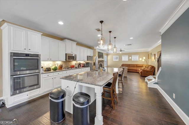 kitchen with an island with sink, light stone counters, a breakfast bar, stainless steel appliances, and a sink