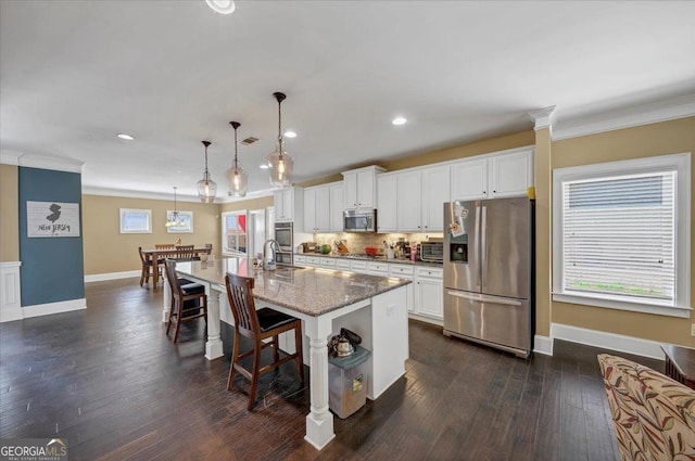 kitchen featuring appliances with stainless steel finishes, crown molding, decorative backsplash, and an island with sink