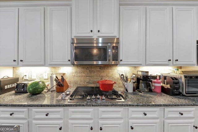 kitchen featuring stainless steel appliances, white cabinetry, and backsplash