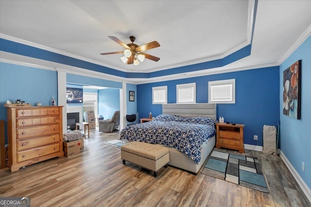 bedroom with multiple windows, a fireplace, and wood finished floors